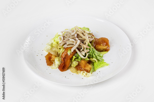 Plate of fresh calamari salad with vegetables isolated at white background.