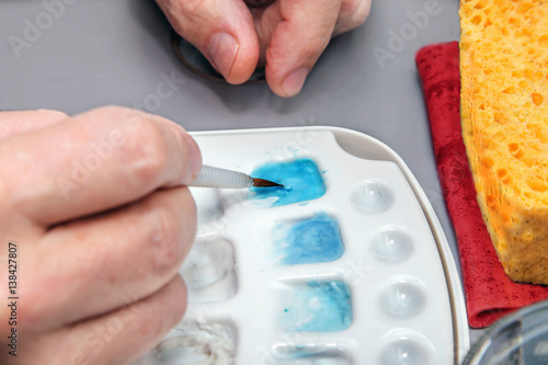 Dentist hand with brush on ceramic glaze for dental model photo