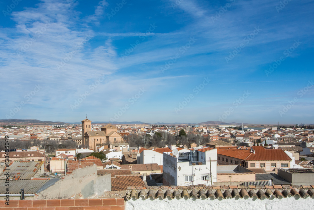 A panoramic view to spanish town Consuegra (Castilla-La Mancha) over the orange tile roofs on sunny day.