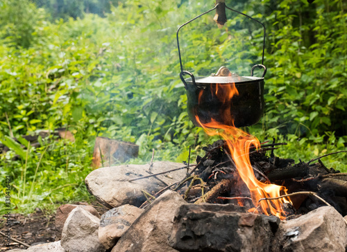 Cooking in caldron. Preparing food on campfire in wild camping. Cooking in a pot on the campfire. Cooking food at a campsite in wood