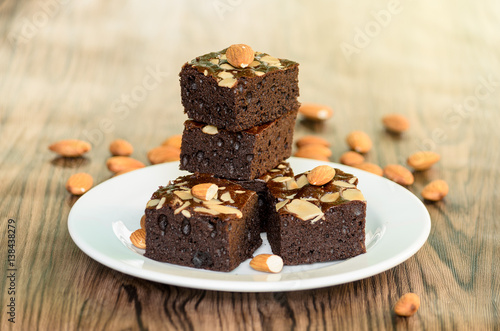 Almond Dark Brownies in white plate on wood table background.