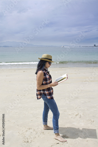 Woman with straw hat and book on the beach photo