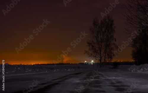 Lonely tree on the roadside on a winter s night on the background of city lights