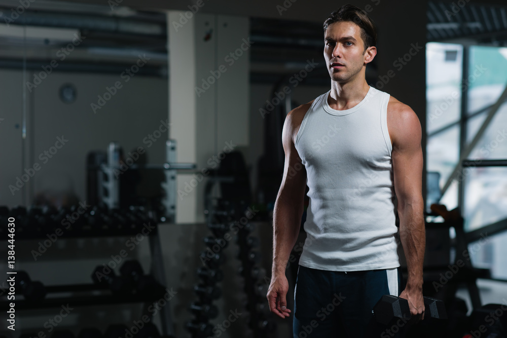 Fit young man exercising with dumbbells in gym Fit young man exercising with dumbbells in gym