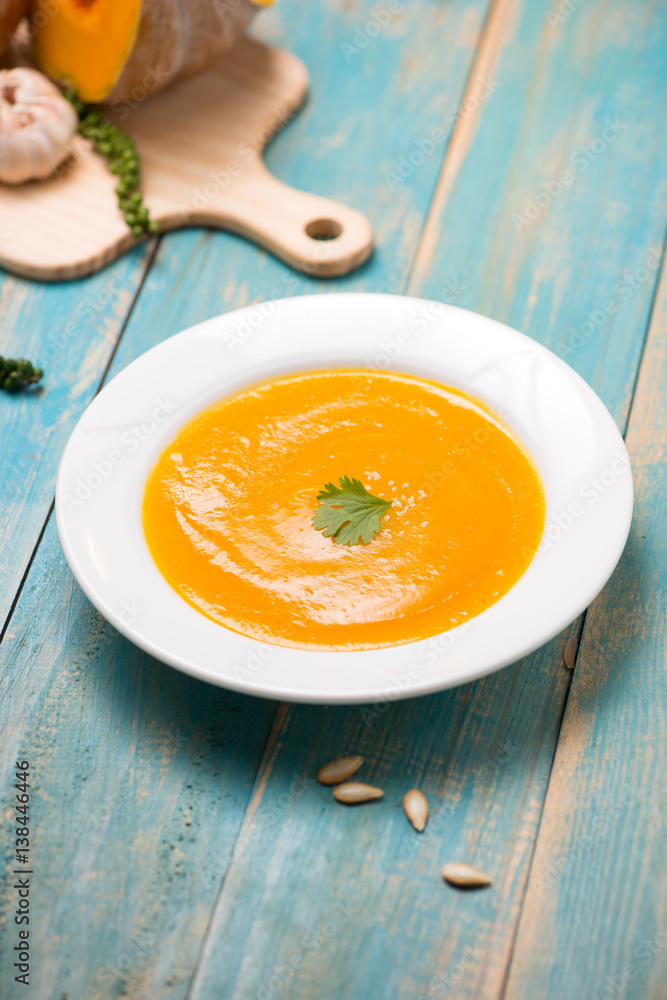 Top view of pumpkin and carrot soup with cream and parsley on blue wooden background. Top view of pumpkin and carrot soup with cream and parsley on blue wooden background.