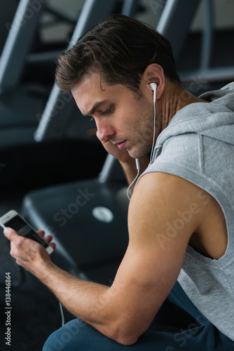 Man using his phone resting after workout in gym