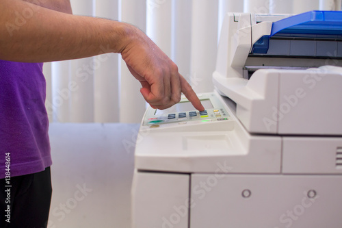 Copier Start - Finger pressing the start button on a multifunction printer or copier.