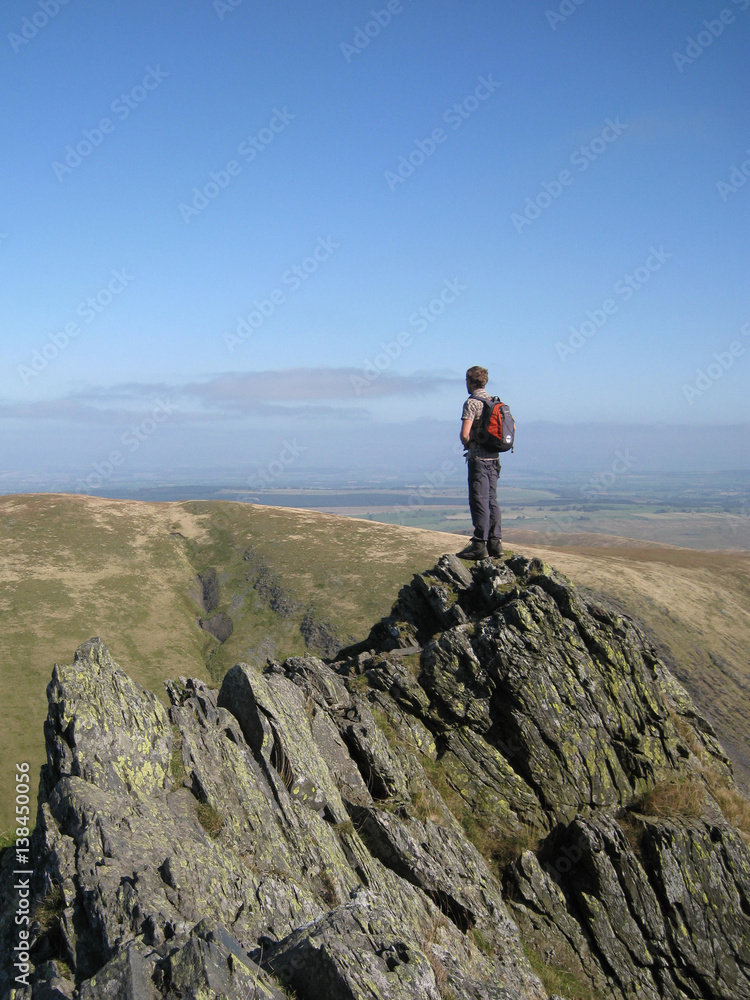 Obraz premium Man looks in to distance from a precarious ledge and contemplates