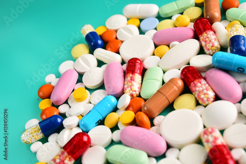 Multicolored pills and tablets on green background