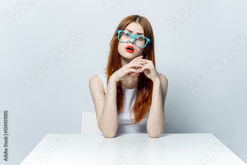 attractive woman in blue glasses is sitting at the table