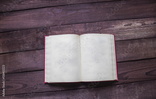 Open red book on wooden desk with soace for text