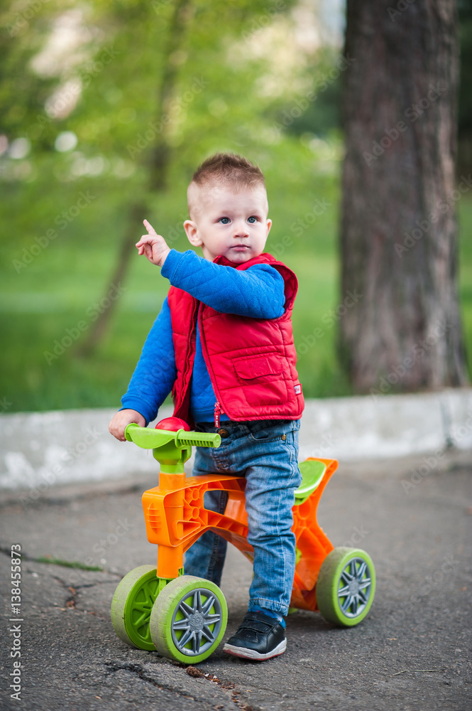 little baby boy in fashionable clothes on a scooter little baby boy in fashionable clothes on a scooter