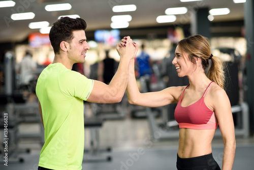 Smiling young man and woman doing high five in gym