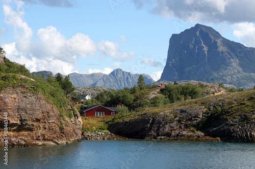 einsames rotes Haus aus Holz in einer kleinen felsigen Bucht mit Steilküste in Helgeland, Nordland, Norwegen photo