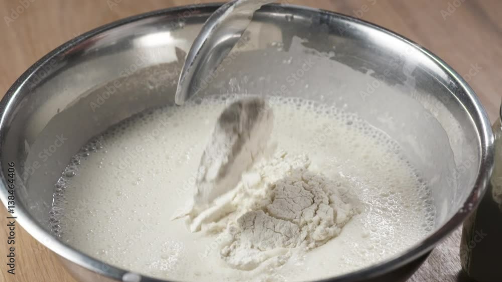 Slow motio of adding flour to milk in stainless steel bowl, 180fps prores footage Slow motio of adding flour to milk in stainless steel bowl, 180fps prores footage