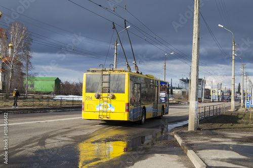 Modern yellow trolley bus on the road - back view