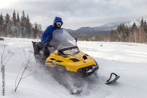 Woman on a snowmobile moving in a winter forest in the mountains of the Southern Urals.