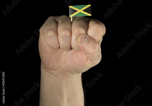 Man hand fist with Jamaican flag isolated on black background