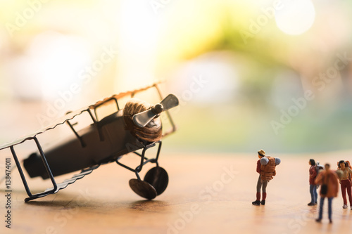 Miniature people : travellers standing on world map in front of vintage airplane for travelling around the world,  exploring on earth background concept.
