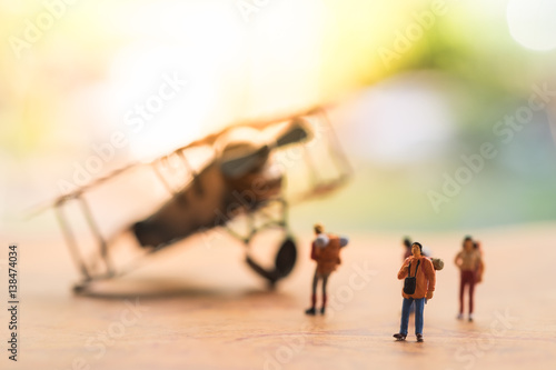 Miniature people : travellers standing on world map in front of vintage airplane for travelling around the world, exploring on earth background concept.