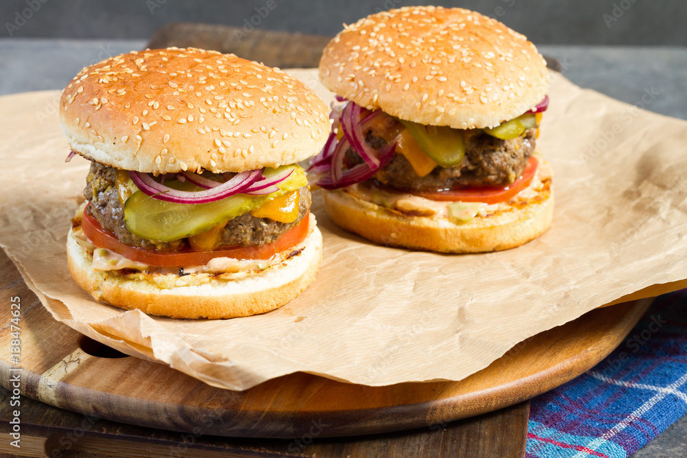 Fresh burger with beef on wooden table and paper. Gray background. Fresh burger with beef on wooden table and paper. Gray background.