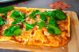 Pizza with basil and cheese on a wooden board.