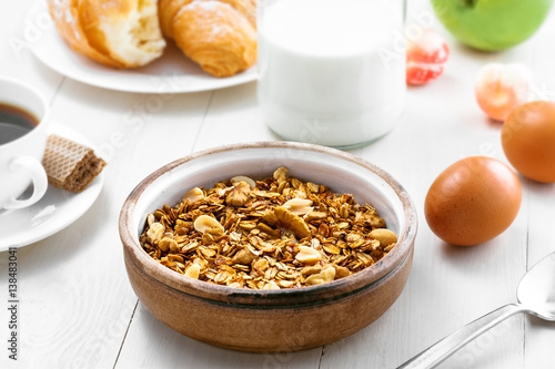 Oatmeal muesli with nuts, croissants, fruits, milk and coffee for delicious breakfast. Traditional healthy meal for breakfast on a table. © Maxim Khytra