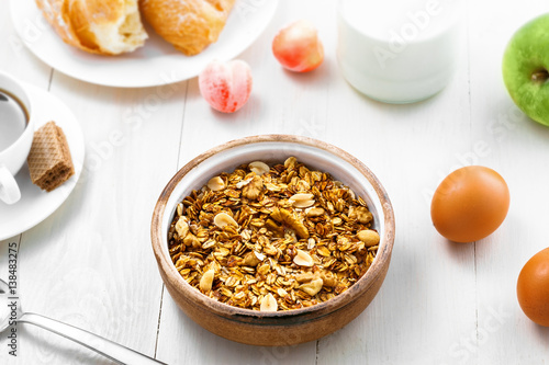 Healthy food for breakfast on a white wooden table. Oatmeal granola with nuts, coffee, croissants, eggs, milk and fruits for delicious healthy meal. Top view. © Maxim Khytra