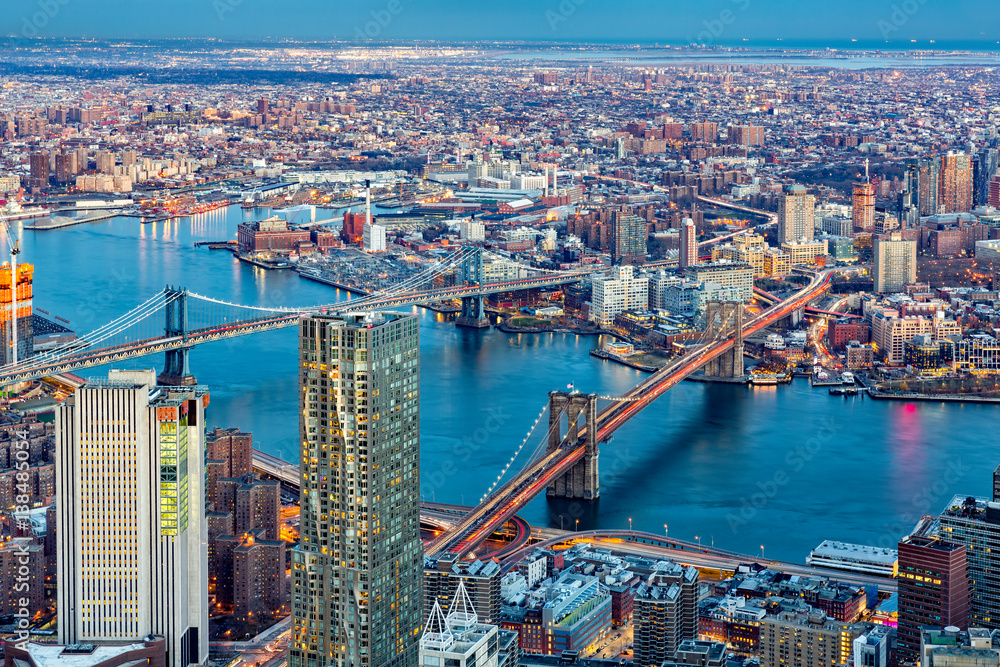 Fototapeta premium Brooklyn and Manhattan bridges span East River at dusk, between Manhattan island and Brooklyn borough