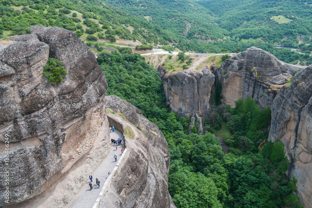 People walking on the path to the top of Meteora monastery, Greece, aerial view People walking on the path to the top of Meteora monastery, Greece, aerial view