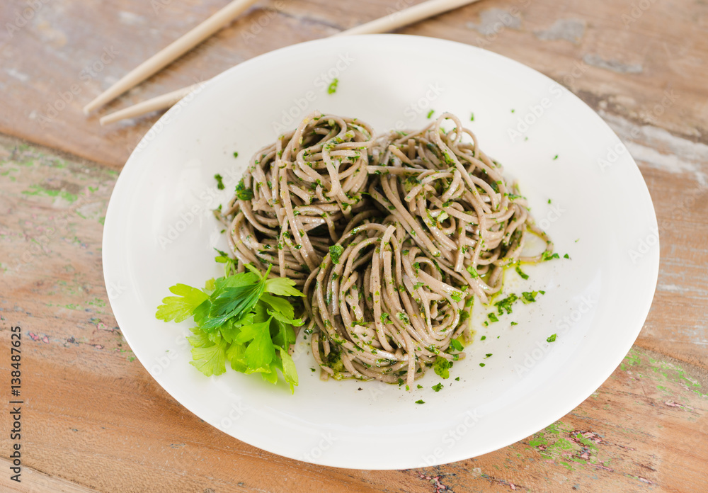 Organic brown noodles cooked in garlic oil, fresh coriander and sea salt. Served wit chopsticks on a whim plate. Organic brown noodles cooked in garlic oil, fresh coriander and sea salt. Served wit chopsticks on a whim plate.