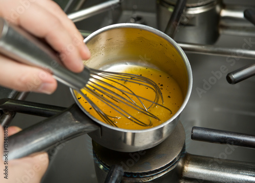 Photos A metal mixing bowl full of fresh chicken stock being reduced over a flaming hob