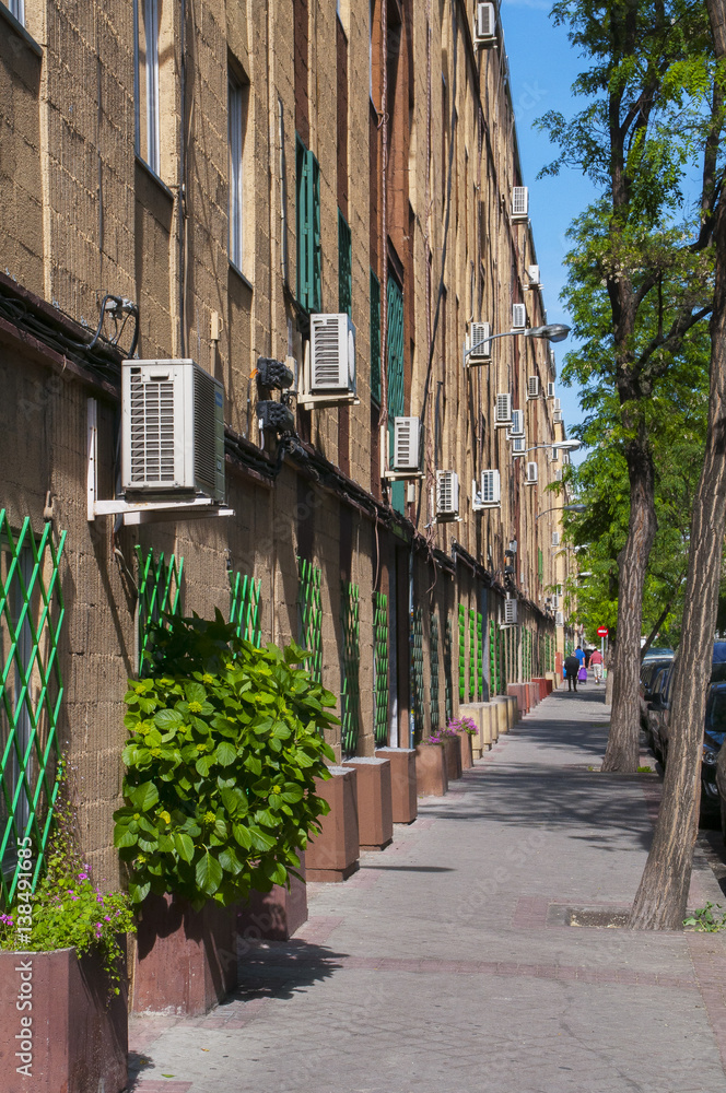 Calle arbolada con edificio con aparatos de aire acondicionado Stock Photo  | Adobe Stock