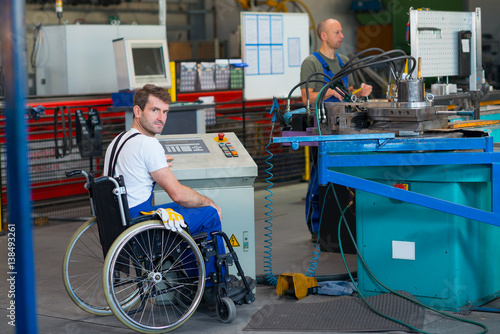 disabled worker in wheelchair in factory and colleague