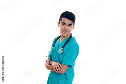 young doctor stands sideways with a stethoscope and keeps hands together