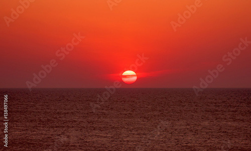 Brightly colored sun during sunset through clouds in the sea