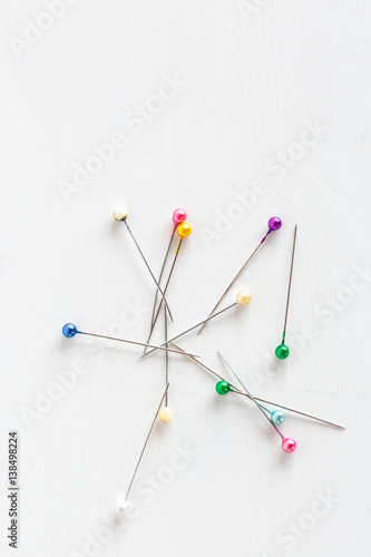 color pins for sewing on a white background, top view.
