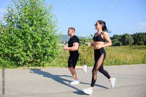 Couple of strong fit man and woman jogging outdoors