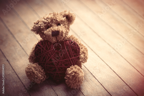 cute fluffy teddy bear with heart shaped toy on the wonderful brown wooden background photo