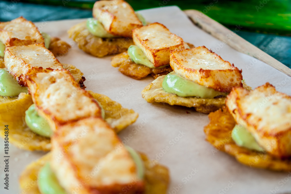 Cheese and avocado tostones, plantain crushed in small portions. In the top a fried cheese. Cheese and avocado tostones, plantain crushed in small portions. In the top a fried cheese.