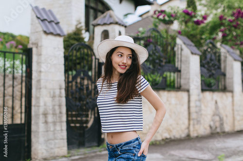 Beautiful girl in stylish jeans and white hat walking in the streets.
