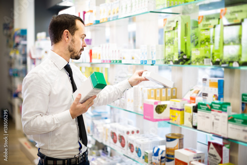 Positive man customer browsing rows of drugs