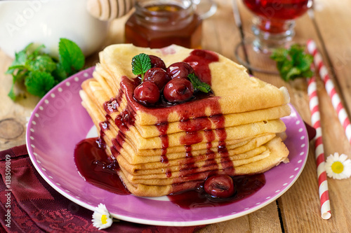 Photos Stack of thin crepes with cherry topping