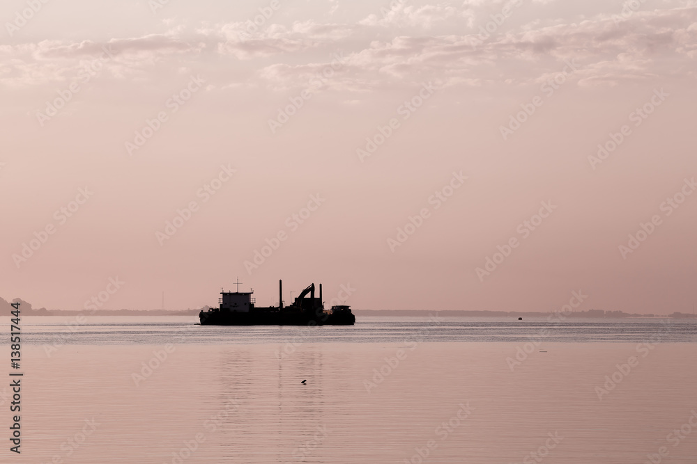 Obraz premium Cargo ship in the sea at dawn