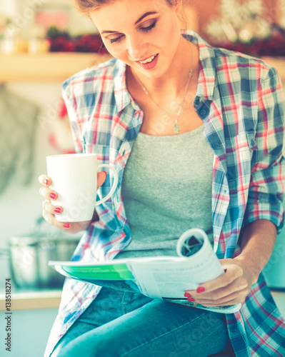 Woman reading mgazine In kitchen at home photo