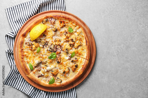 Tasty seafood pizza and napkin on grey background