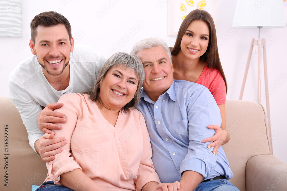 Young couple with middle aged parents on sofa in the room Young couple with middle aged parents on sofa in the room