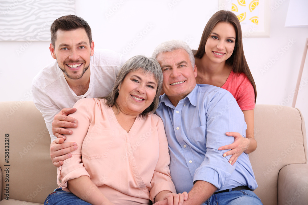 Young couple with middle aged parents on sofa in the room Young couple with middle aged parents on sofa in the room