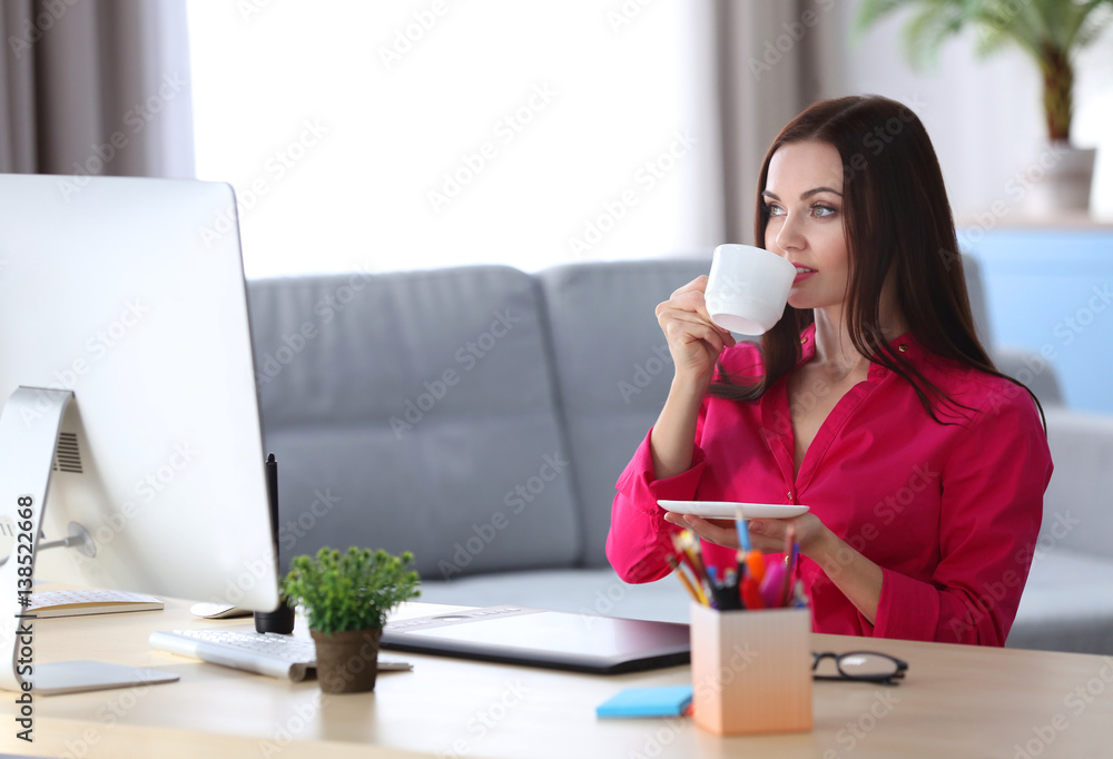 Young beautiful designer drinking coffee in office Young beautiful designer drinking coffee in office