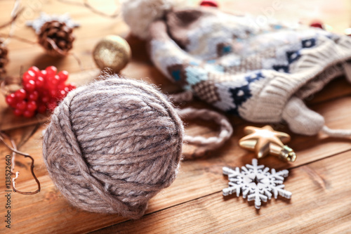 Yarn ball, knitted hat and Christmas decorations on wooden table